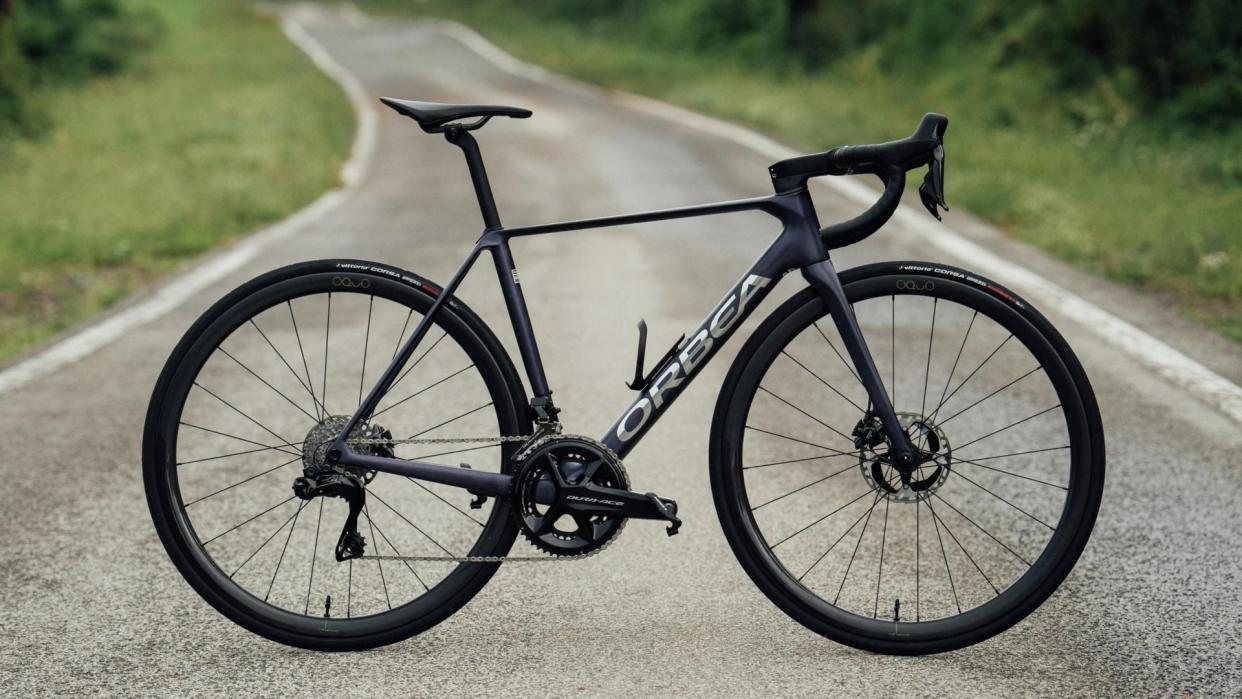  The Orbea Orca OMX on a tarmac road with greenery either side  