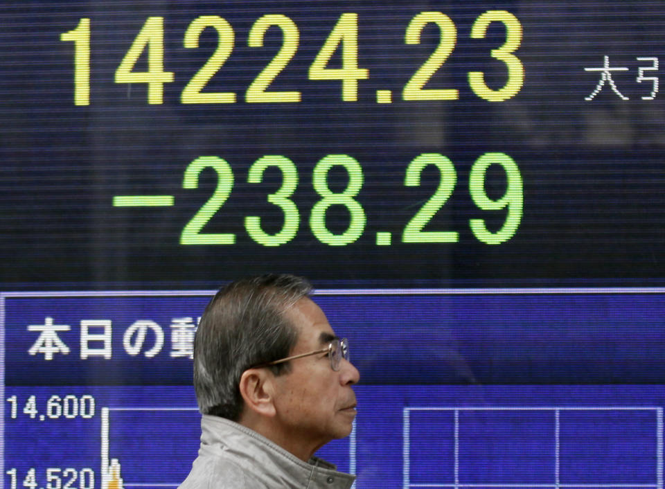 A man walks by an electronic stock board of a securities firm in Tokyo, Thursday, March 20, 2014. Asian stocks inched down Thursday after comments from the new head of the Federal Reserve suggested U.S. interest rates could rise sooner than financial markets were anticipating. (AP Photo/Koji Sasahara)