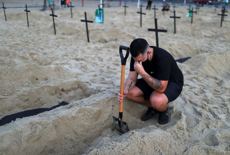 Un activista de la ONG Río de Paz con una máscara protectora reacciona mientras asiste a una manifestación durante la cual se excavaron cien tumbas en la playa de Copacabana que simboliza a los muertos por la enfermedad del coronavirus (COVID-19), en Río de Janeiro