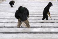 Paid volunteers clear snow from the bleachers at Lambeau Field in Green Bay, Wisconsin, the home field of the Green Bay Packers of the National Football League (NFL), December 21, 2013. In winter months, the team calls on the help of hundreds of citizens, who also get paid a $10 per-hour wage, to shovel snow and ice from the seating area ahead of games, local media reported. The Packers will host the Pittsburgh Steelers on Sunday, December 22. REUTERS/Mark Kauzlarich (UNITED STATES - Tags: ENVIRONMENT SPORT FOOTBALL)