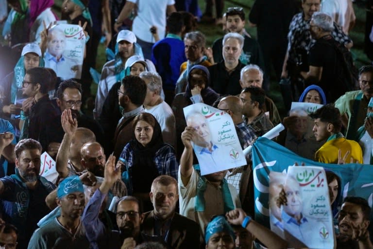 Supporters of reformist Iranian presidential candidate Massoud Pezeshkian raise his portrait during a rally in Tehran (RAHEB HOMAVANDI)