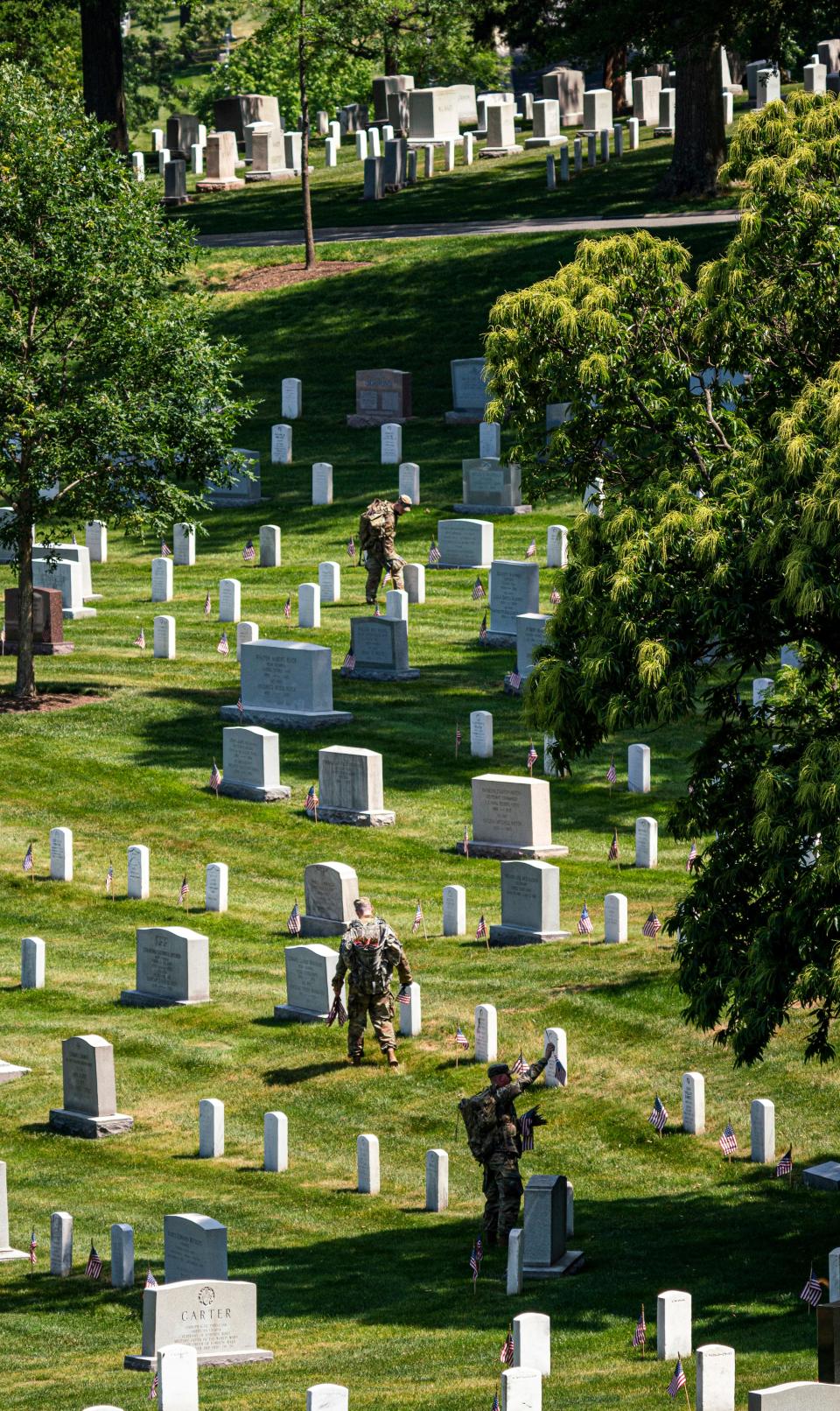 Members of the 3rd United States Infantry Regiment, also known as The Old Guard, place flags in front of each headstone as part of the "Flags In" ceremony at Arlington National Cemetery in Arlington, Va. on Thursday, May 27, 2021. Since 1948, The Old Guard has placed flags at each headstone in honor of Memorial Day.