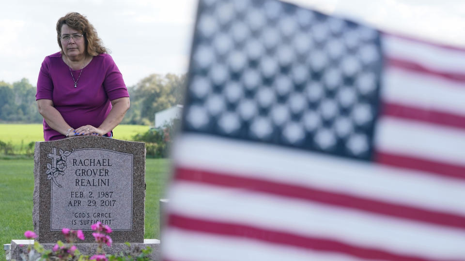 Sharon Grover stands over the grave of her daughter, Rachael, Tuesday, Sept. 28, 2021, at Fairview Cemetery in Mesopotamia, Ohio. Grover believes her daughter started using prescription painkillers around 2013 but missed any signs of her addiction as her daughter, the oldest of five children, remained distanced. (AP Photo/Tony Dejak)