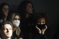 Spectators, some of them wearing sanitary masks, follow the Dolce & Gabbana women's Fall Winter 2020-21 show, in Milan, Italy, Sunday, Feb. 23, 2020. After Giorgio Armani's last-minute decision to show his latest collection in an empty theater due to concerns about the new virus, the rest of Milan's runway shows scheduled for Sunday are to go ahead as planned, fashion officials confirmed. (AP Photo/Antonio Calanni)