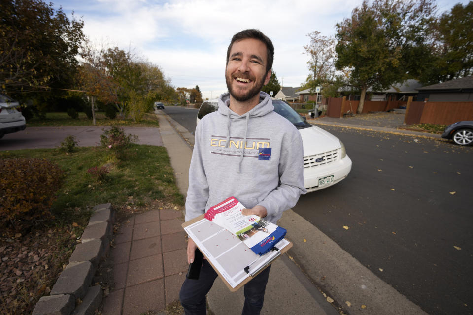 Vote canvasser Zach Martinez carries information as he works along Ash Street to reach voters in their homes late Tuesday, Nov. 1, 2022, in northeast Denver. Coloradans are taking the state's housing crisis into their own hands by turning to local and statewide ballot measures intended to quell the soaring costs. (AP Photo/David Zalubowski)