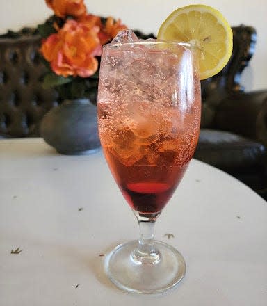 A dirty shirley on a white table with lemon garnish