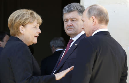 Ukraine president-elect Petro Poroshenko (C) looks on as German Chancellor Angela Merkel (L) talks to Russian President Vladimir Putin after a group photo for the 70th anniversary of the D-Day landings at Benouville Castle, June 6, 2014. REUTERS/Regis Duvignau