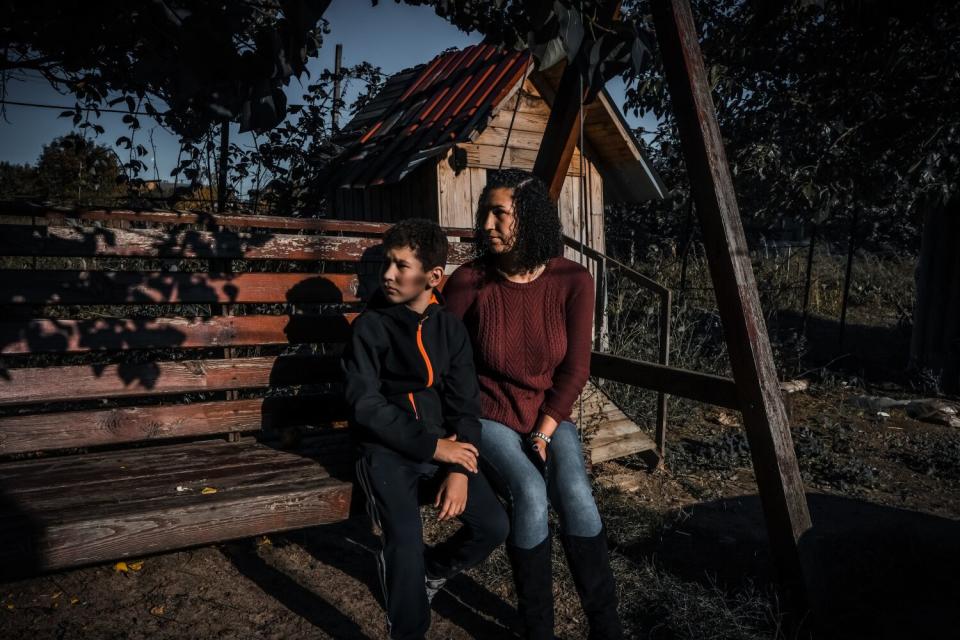 A woman and a boy sit on a bench swing