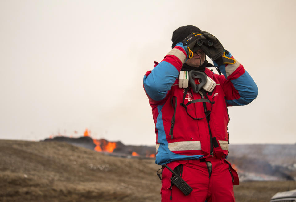 A member of the Search and Rescue Team, Bjorgunasveit scans the horizon near a new fissure on a volcano on the Reykjanes Peninsula in southwestern Iceland, Monday, April 5, 2021. The new fissure has opened up at the Icelandic volcano that began erupting last month, prompting the evacuation of hundreds of hikers who had come to see the spectacle. Officials say the new fissure is about 500 meters (550 yards) long and about one kilometer (around a half-mile) from the original eruption site in the Geldinga Valley (AP Photo/Marco Di Marco)