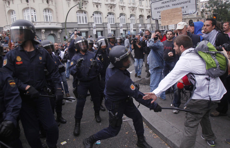 File - In this Sept. 25, 2012 file photo, a police officer hits a man with a baton during a march to the parliament against austerity measures announced by the Spanish government, in Madrid. Spain's government said Friday Oct. 19, 2012 it is considering a ban on photographing, filming and reproducing images of police and state security forces while “in the exercise of their functions.” Deputy Prime Minister Soraya Saenz de Santamaria said that after months of television and internet viewing of sometimes violent clashes between police and demonstrators a balance had to be struck “between citizens' right to protest” and a need “to uphold the integrity of state security forces.” (AP Photo / Andres Kudacki, File)