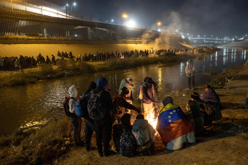 Venezuelan immigrants warm by a fire after hundreds of other migrants surged across the Rio Grande into El Paso, Texas to seek asylum on December 19, 2022 as seen from Ciudad Juarez, Mexico.