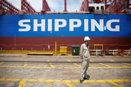 A labourer stand in front a new ship at Shanghai Waigaoqiao Shipbuilding Co., Ltd. in Shanghai, China June 15, 2017. Picture taken June 15, 2017. REUTERS/Aly Song