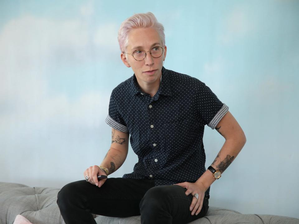 io tillet wright sitting on the top of a sofa in front of a cloud background