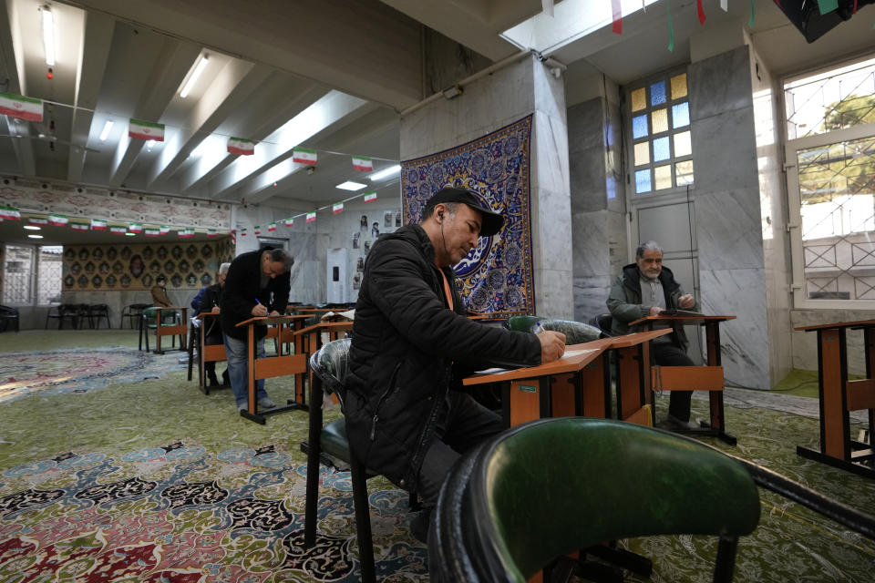 Voters fill out their ballots during the parliamentary and Assembly of Experts elections at a polling station in Tehran, Iran, Friday, March 1, 2024. Iran on Friday held the country's first election since the mass 2022 protests over mandatory hijab laws after the death in police custody of Mahsa Amini, with questions looming over just how many people will turn out at the polls. (AP Photo/Vahid Salemi)