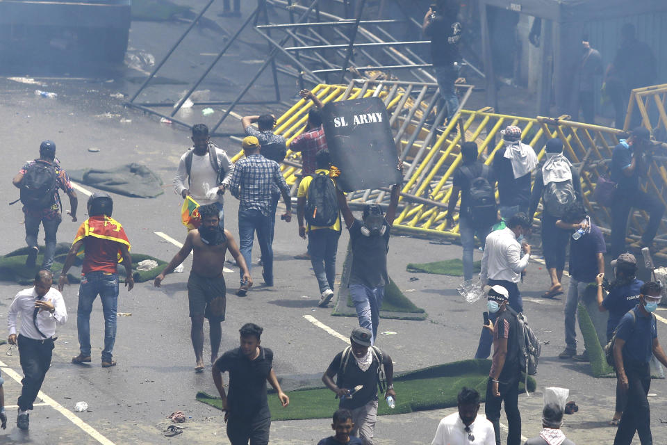 Protesters react after police fired tear gas to disperse them in Colombo, Sri Lanka, Saturday, July 9, 2022. Sri Lankan protesters demanding that President Gotabaya Rajapaksa resign forced their way into his official residence on Saturday, a local television report said, as thousands of people took to the streets in the capital decrying the island nation's worst economic crisis in recent memory. (AP Photo/Amitha Thennakoon)