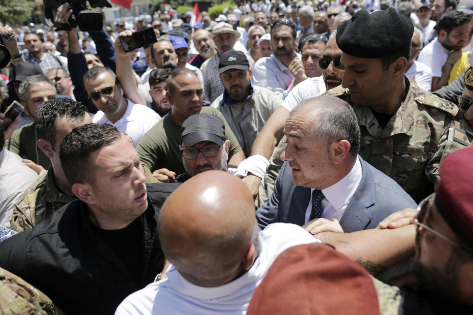 Lebanese Defense Minister Elias Bou Saab, right, meets Lebanese retired soldiers as they protest in front of the government building during a cabinet meeting to discuss an austerity budget, in Beirut, Lebanon, Friday, May 10, 2019. Dozens of Lebanese military and security veterans burned tires and shouted angrily outside government offices on Friday, their second protest in less than two weeks amid fears a proposed austerity budget may affect their pensions and benefits. (AP Photo/Hassan Ammar)