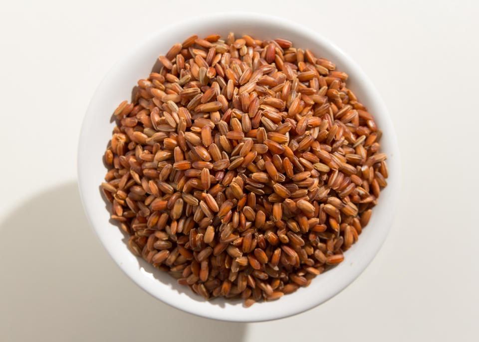 Oryza sativa is scientific name of Bhutanese Red Rice seed. Also known as Arroz Vemelho (portuguese). Top view of grains in a bowl. White background.