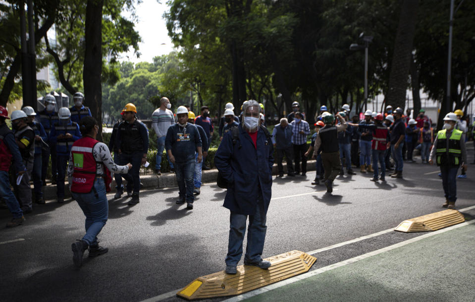 Employees stand outside of their work building after a 7.5 earthquake, in Mexico City, Tuesday, June 23, 2020. The earthquake centered near the resort of Huatulco in southern Mexico swayed buildings Tuesday in Mexico City and sent thousands into the streets.(AP Photo/Fernando Llano)