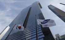 A flag of Samsung flutters at half-mast next to the South Korean national flag outside of Samsung's Seocho office building in Seoul, South Korea, Wednesday, Oct. 28, 2020. Lee Kun-Hee, late Samsung Electronics chairman who transformed the small television maker into a global giant of consumer electronics but whose leadership was also marred by corruption convictions, died on Sunday at the age of 78. (AP Photo/Lee Jin-man)