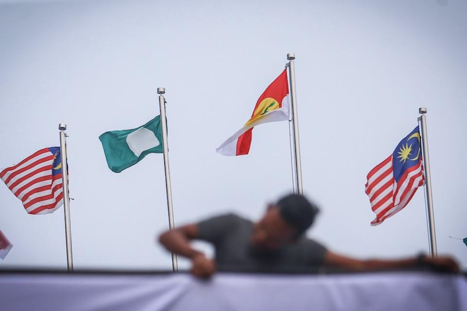 A man hangs Umno, PAS and Malaysia flags at Putra World Trade Centre in Kuala Lumpur September 12, 2019, ahead of the Muslim Unity Rally. — Picture by Hari Anggara