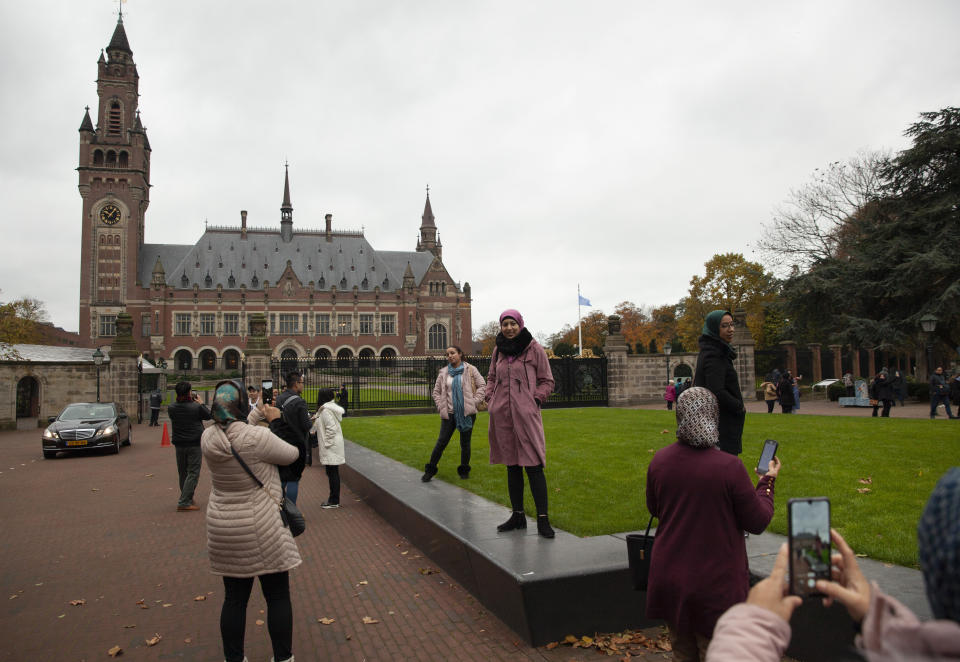 Tourists take pictures of the Peace Palace, rear, which houses the International Court in The Hague, Netherlands, Monday, Nov. 11, 2019, where Gambia filed a case at the United Nations' highest court accusing Myanmar of genocide in its campaign against the Rohingya Muslim minority. A statement released Monday by lawyers for Gambia says the case also asks the International Court of Justice to order measures "to stop Myanmar's genocidal conduct immediately." (AP Photo/Peter Dejong)