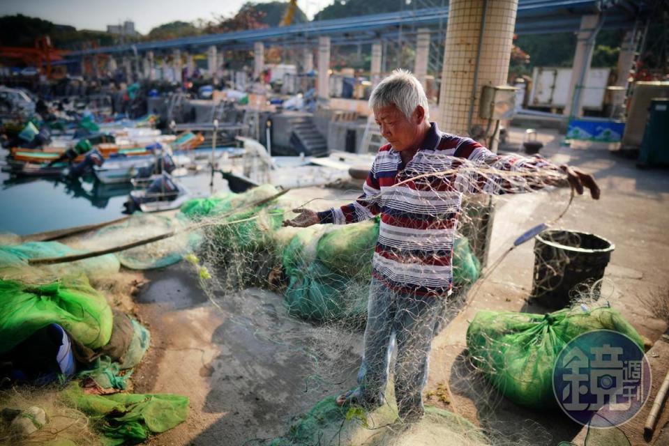 吳大頭在鳳鼻頭港一邊整理漁網，一邊對我們訴說面對遷村的心情。