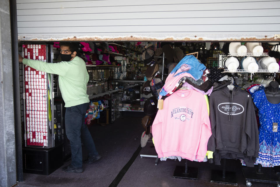 Mohammad Ikram closes a large door to his business Hot Stop, fully stocked but closed during the coronavirus pandemic, on the boardwalk in Atlantic City, N.J., Tuesday, April 28, 2020. (AP Photo/Matt Rourke)