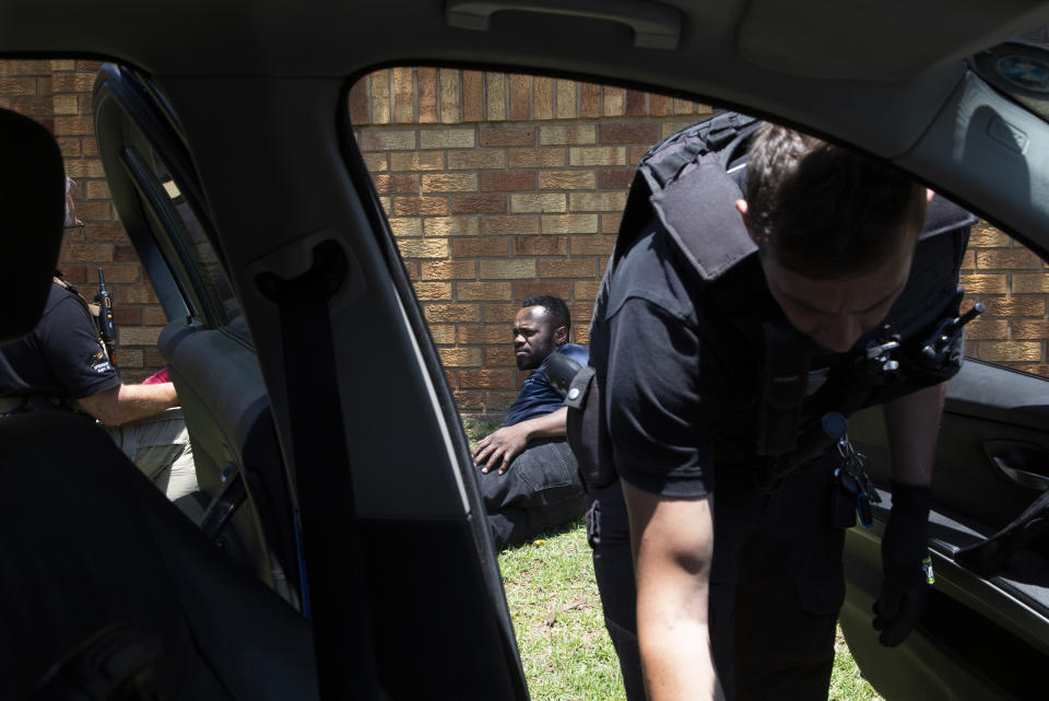 A men, on the ground, suspected of driving a stolen vehicle, is apprehended by private security personal, right, in a suburb east of Johannesburg, South Africa, Friday, Dec. 1, 2023. Experts have warned that the South African police are losing the battle against crime and that has led those citizens who can afford it, to turn to a booming private security industry. (AP Photo/Denis Farrell)
