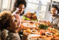 cheerful african american girl with her parents at dining table