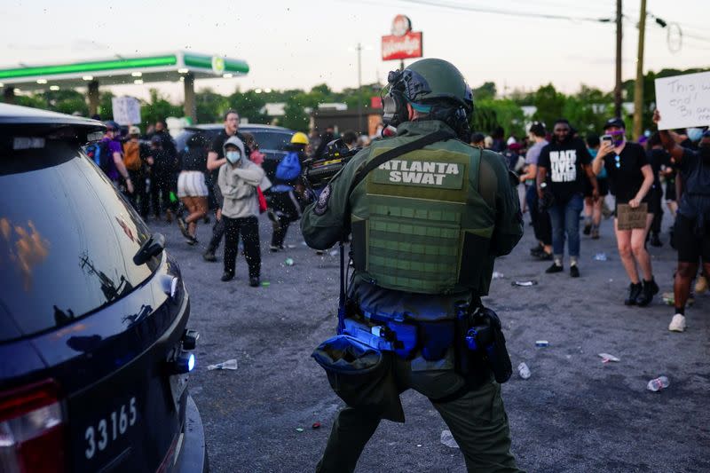 An Atlanta SWAT officer draws his weapon during a rally against racial inequality and the police shooting death of Rayshard Brooks, in Atlanta