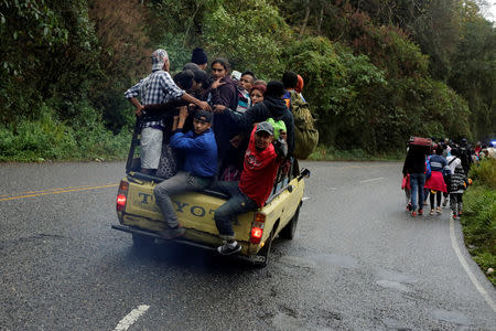 Migrants from Honduras, part of a new caravan from Central America trying to reach the United States, walk along a road as others ride in a truck as they hitch a ride, in Esquipulas, Guatemala January 16, 2019. REUTERS/Jorge Cabrera