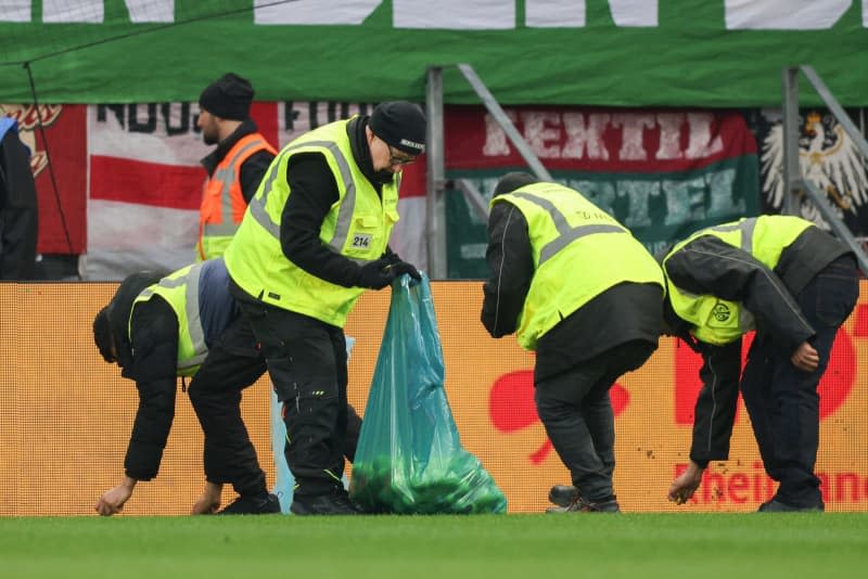 Stewards collect the tennis balls thrown by Augsburg fans onto the pitch in protest against the German Football League's (DFL) plans to bring in investors, during the German Bundesliga soccer match between FSV Mainz 05 and FC Augsburg at the Mewa Arena. Jürgen Kessler/dpa