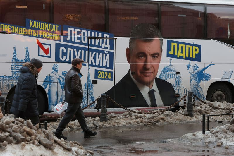 FILE PHOTO: People walk past a bus with a portrait of presidential candidate Leonid Slutsky in Saint Petersburg