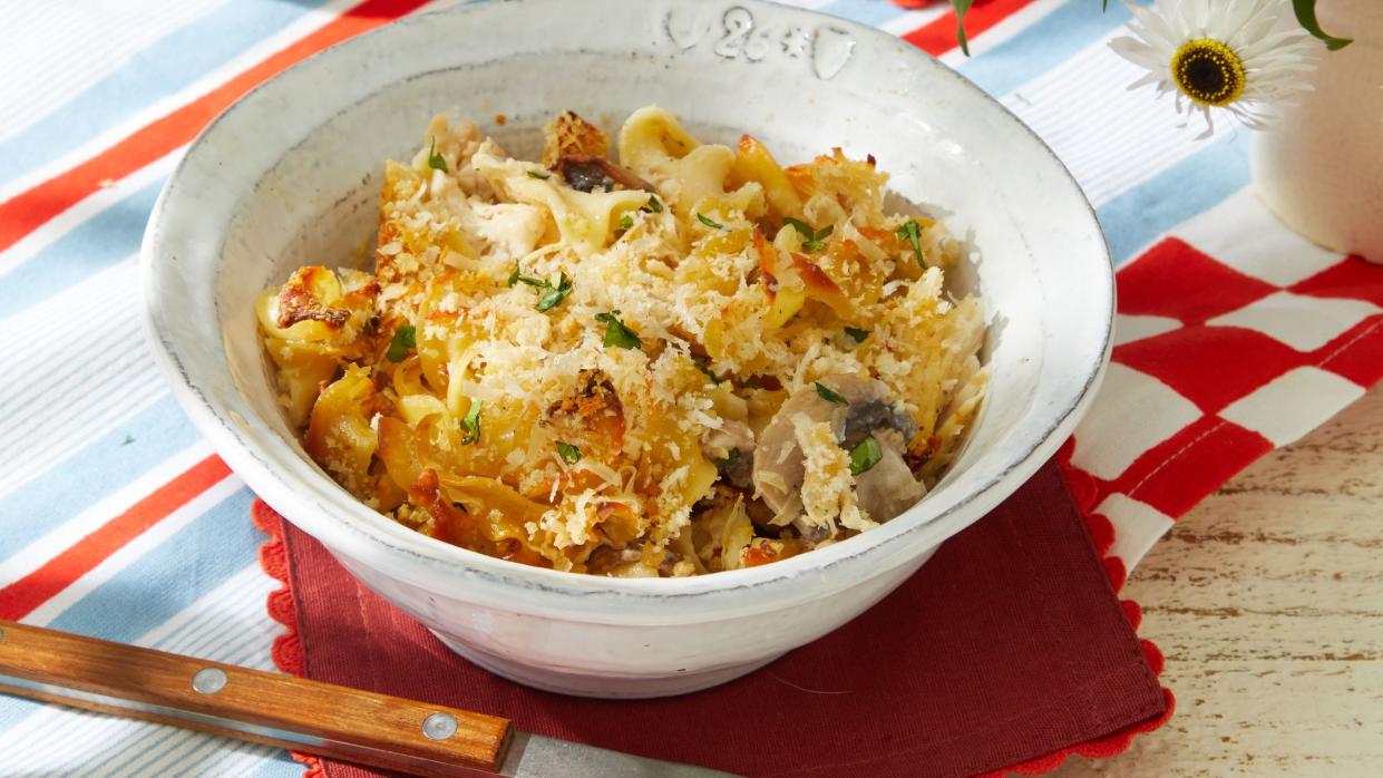 a table with bowls of chicken tetrazini and a glass of beer