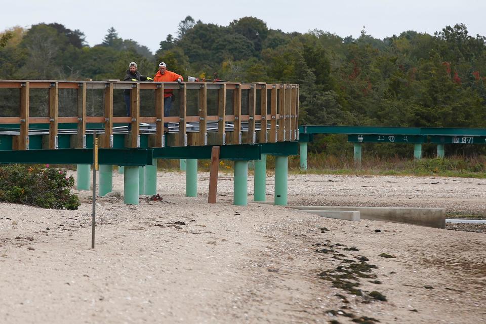 Mark Correia and Billy Phillips of D. W. White install the guardrails for the elevated bike path crossing Mattapoisett River and Eel Pond in Mattapoisett whose planks had to be removed after warping.