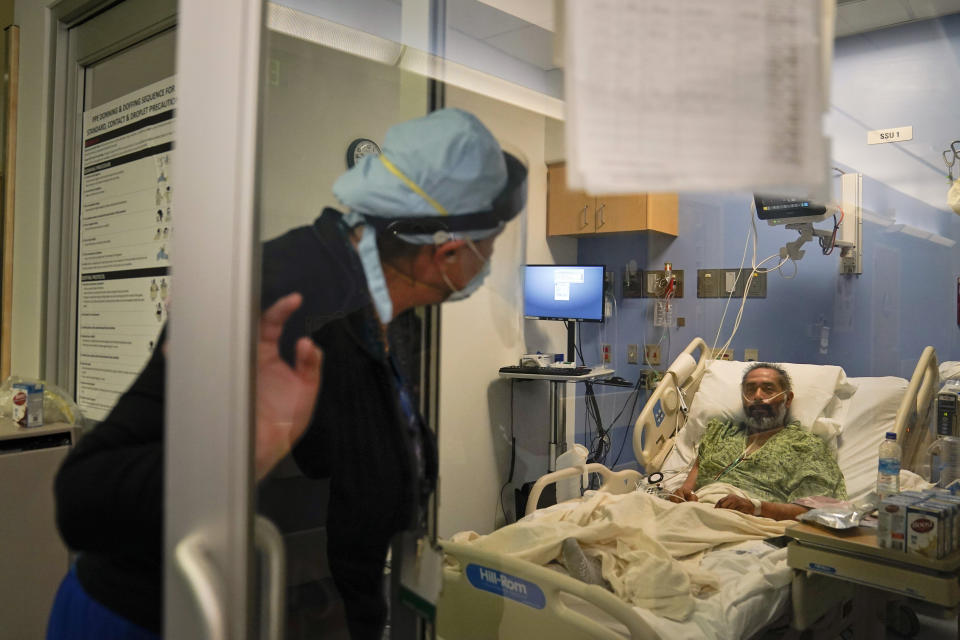 Registered nurse Kobie Walsh, left, checks on a COVID-19 patient at St. Joseph Hospital in Orange, Calif. Thursday, Jan. 7, 2021. The state's hospitals are trying to prepare for the possibility that they may have to ration care for lack of staff and beds — and hoping they don't have to make that choice, as many hospitals strain under unprecedented caseloads. (AP Photo/Jae C. Hong)