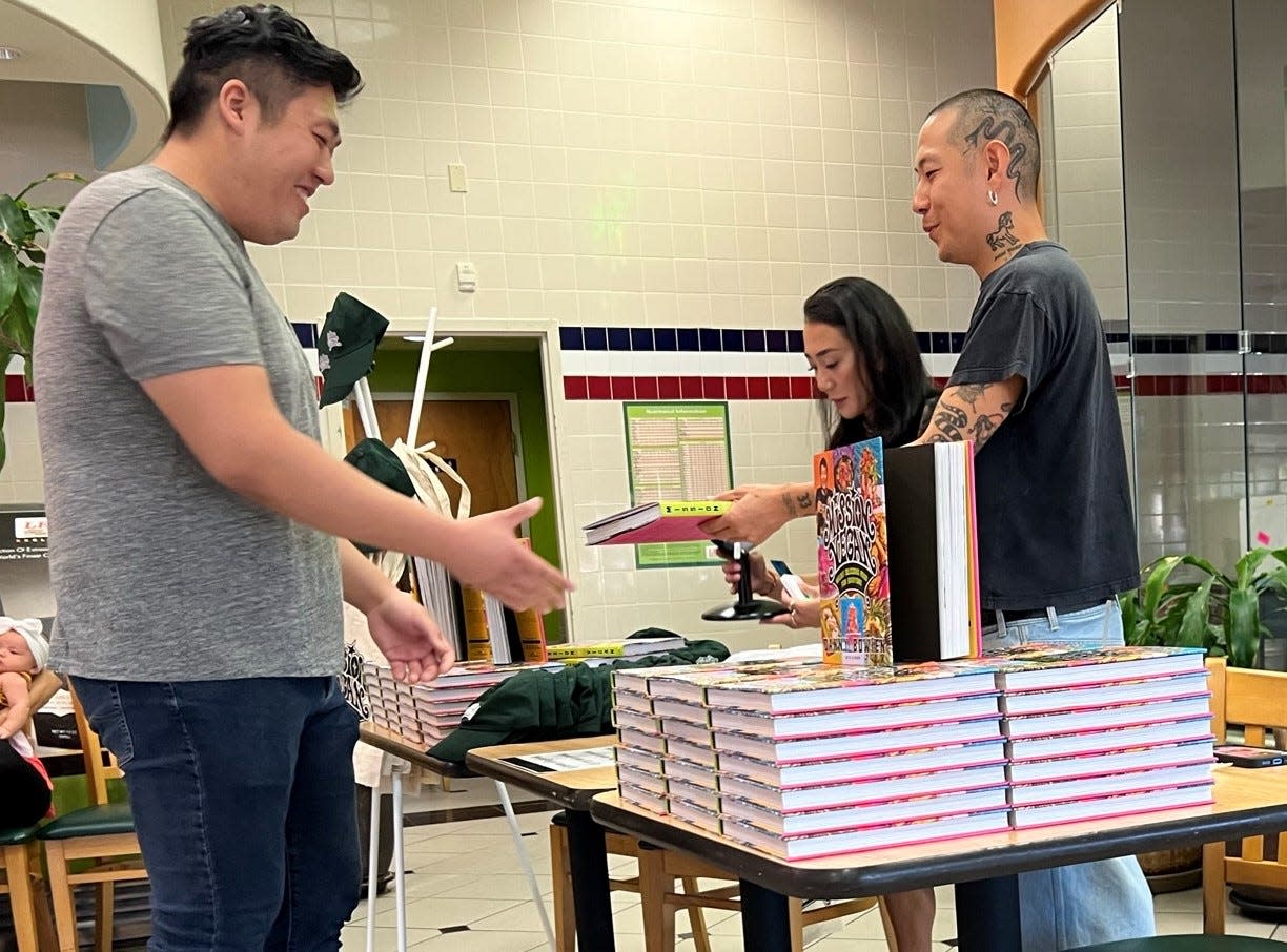 Celebrity chef Danny Bowien hands a a signed book to a fan during a signing event at Lee's Sandwiches in Oklahoma City