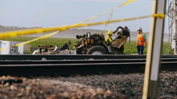 PHOTO: Workers chat behind the remnants of the vehicle where an Amtrak train derailed on June 27, 2022, in Mendon, Mo. (Chase Castor/Getty Images)