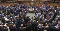Britain's Prime Minister Boris Johnson, centre left, begins to stand, to deliver a statement to lawmakers inside a crowded House of Commons in London, Saturday Oct. 19, 2019. At a rare weekend sitting of Parliament, Johnson implored legislators to ratify the Brexit deal he struck this week with the other 27 EU leaders. (House of Commons via AP)