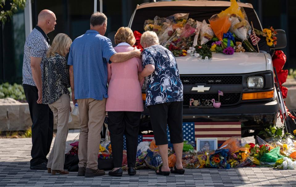 Family members of Marion County Deputy John Durm look at a memorial for him outside the Criminal Justice Center in Indianapolis on Friday, July 14, 2023, after an initial hearing for the man accused of his murder. Orlando Mitchell is accused of fatally strangling Durm with his handcuff chain before stealing a jail transport van and crashing it in an escape attempt July 10.