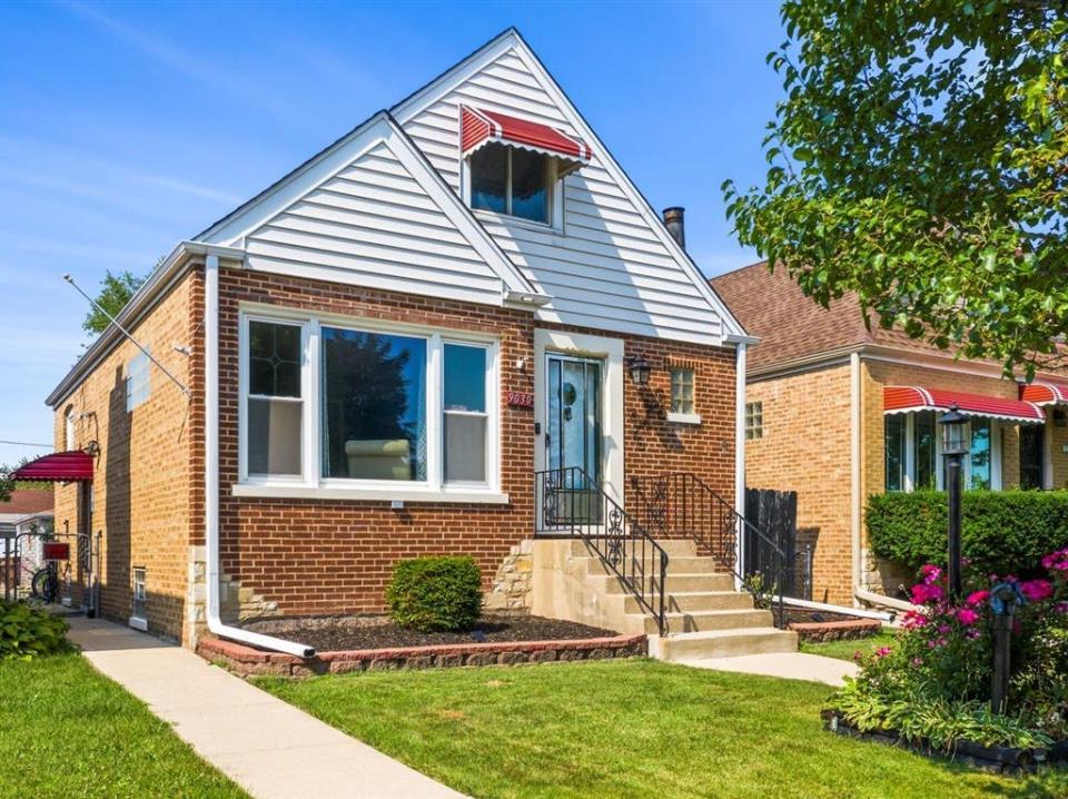 The exterior of the house for sale near Chicago, Illinois with trees and flowers on the lawn