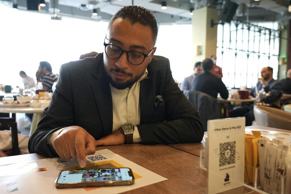 Mohamed Younis, the manager of Hadoota Masreya Restaurant, checks his phone, in Dubai, United Arab Emirates, Sept. 5, 2022. The restaurant employs Egyptian chefs and waiters but caters to a wide variety of customers from around the world. “I have a lot of staff whose families rely on the income they make from the restaurant and a big portion of their incomes are sent back home so people there can live," said Younis. (AP Photo/Malak Harb)