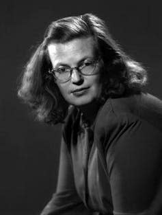 A young woman in 1940 dressed plainly with round owlish glasses.