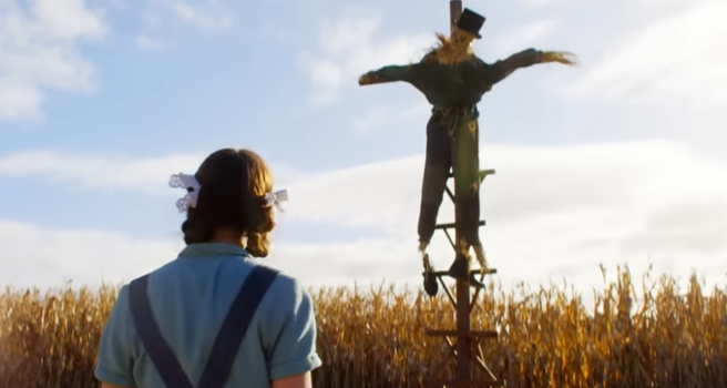 Pearl looking at a scarecrow in a field