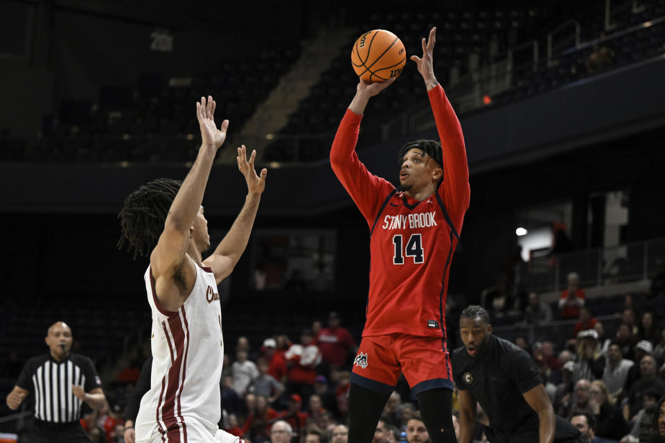 Stony Brook guard Tyler Stephenson-Moore (14) attempts a three point basket against Charleston forward Frankie Policelli during the first half of NCAA college basketball game in the championship of the Coastal Athletic Association conference tournament, Tuesday, March 12, 2024, in Washington. (AP Photo/Terrance Williams)