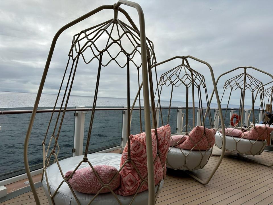 Egg-shaped hanging chairs with cushions on cruise deck overlooking the water