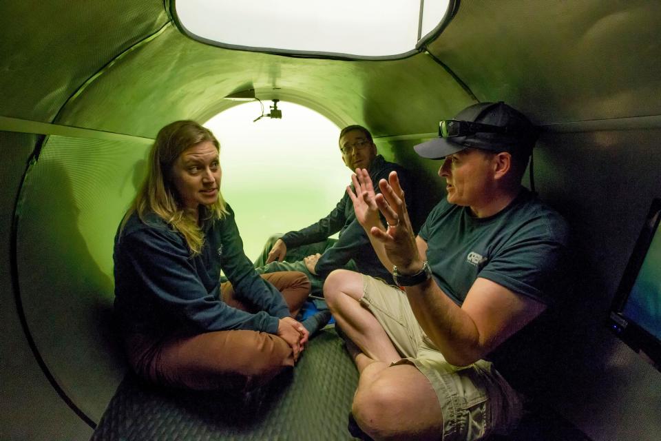 In this May 18, 2017 photo, Director of Marine Operations for OceanGate, Inc., David Lochridge, right, describes diving at great depths to Bonnie Carl and Josh Dean as they sit in the sub Cyclops1, submerged in the waters of the Port of Everett Marina, in Wash. OceanGate plans to carry paying customers on dives to the Titanic in 2018. (Andy Bronson/The Herald via AP)