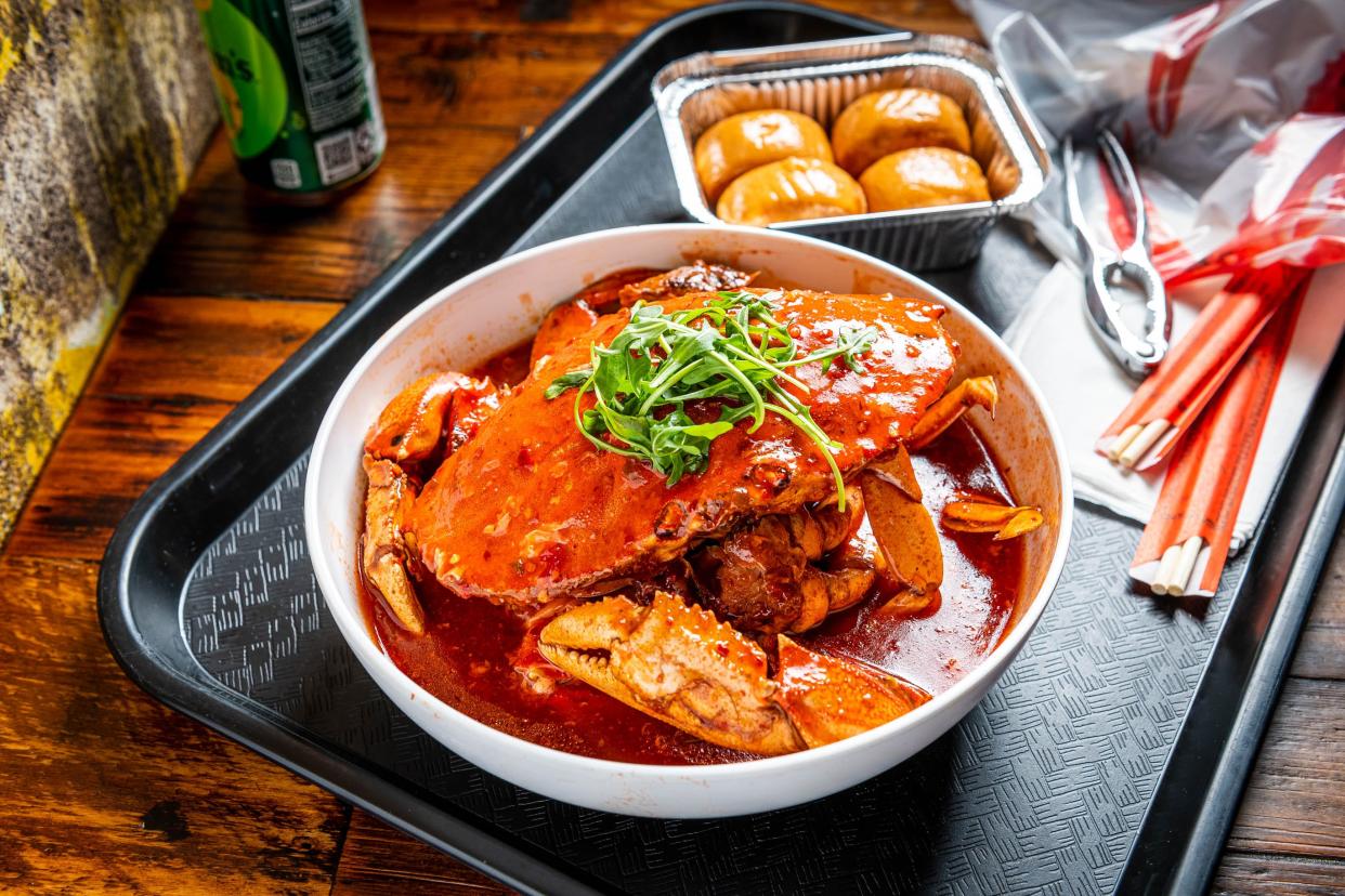 A crab in a bowl of red broth on a tray.