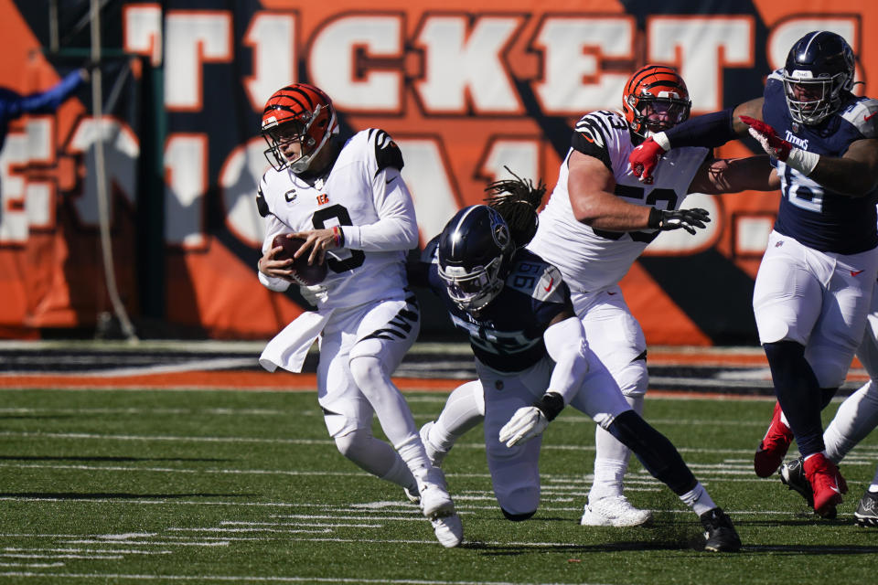 Cincinnati Bengals quarterback Joe Burrow (9) runs out of the tackle of Tennessee Titans' Jadeveon Clowney (99) during the first half of an NFL football game, Sunday, Nov. 1, 2020, in Cincinnati. (AP Photo/Bryan Woolston)