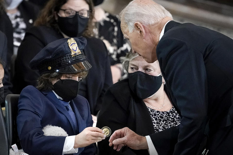 President Joe Biden gives a coin to Logan Evans, son of late U.S. Capitol Police officer William "Billy" Evans, during a memorial service as Evans lies in honor in the Rotunda at the U.S. Capitol, Tuesday, April 13, 2021 in Washington. (Drew Angerer/Pool via AP)